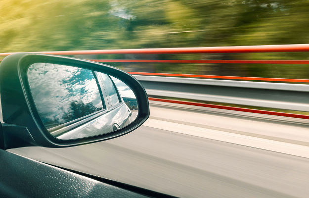 Seitenspiegel eines fahrenden Autos mit verschwommener Landschaft als Symbol für Geschwindigkeit, Vorwärtsbewegung und effizientes Recruiting bei Dashing.