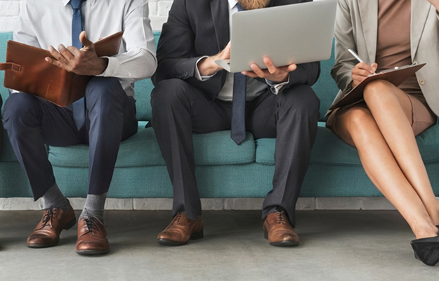 Drei Personen sitzen nebeneinander und arbeiten mit Laptop und Unterlagen als Darstellung strukturierter Kandidatenbewertung und professioneller Recruiting-Prozesse bei Dashing.